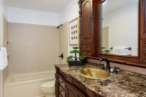 a bathroom with a granite countertop sink a toilet and bathtub