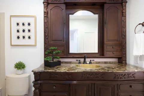a bathroom with a granite countertop sink a toilet and a mirror