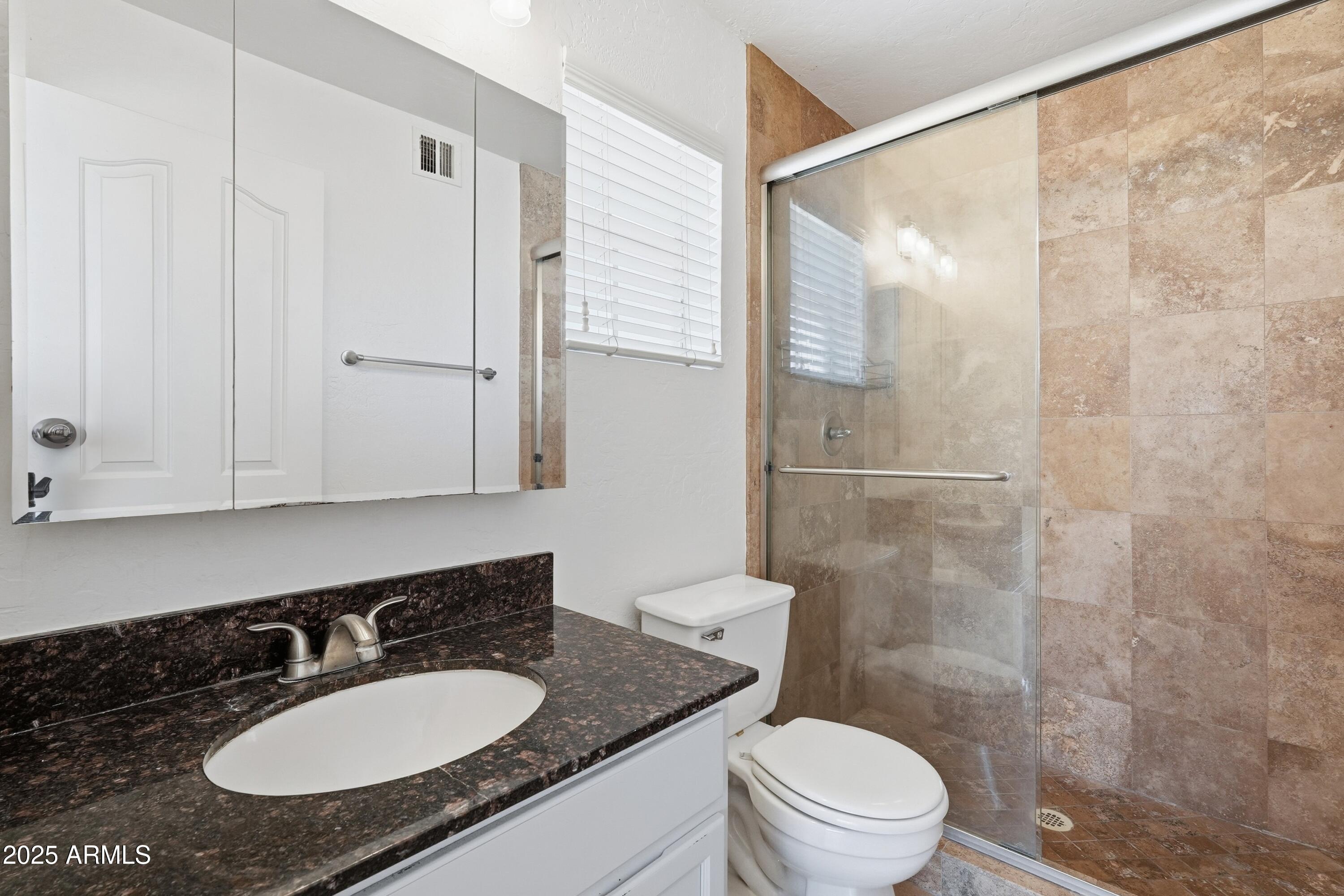 14145 North 92nd Street, Unit 2028 Scottsdale, AZ 85260 - Photo 15 of 24 a bathroom with a granite countertop sink toilet a mirror and shower