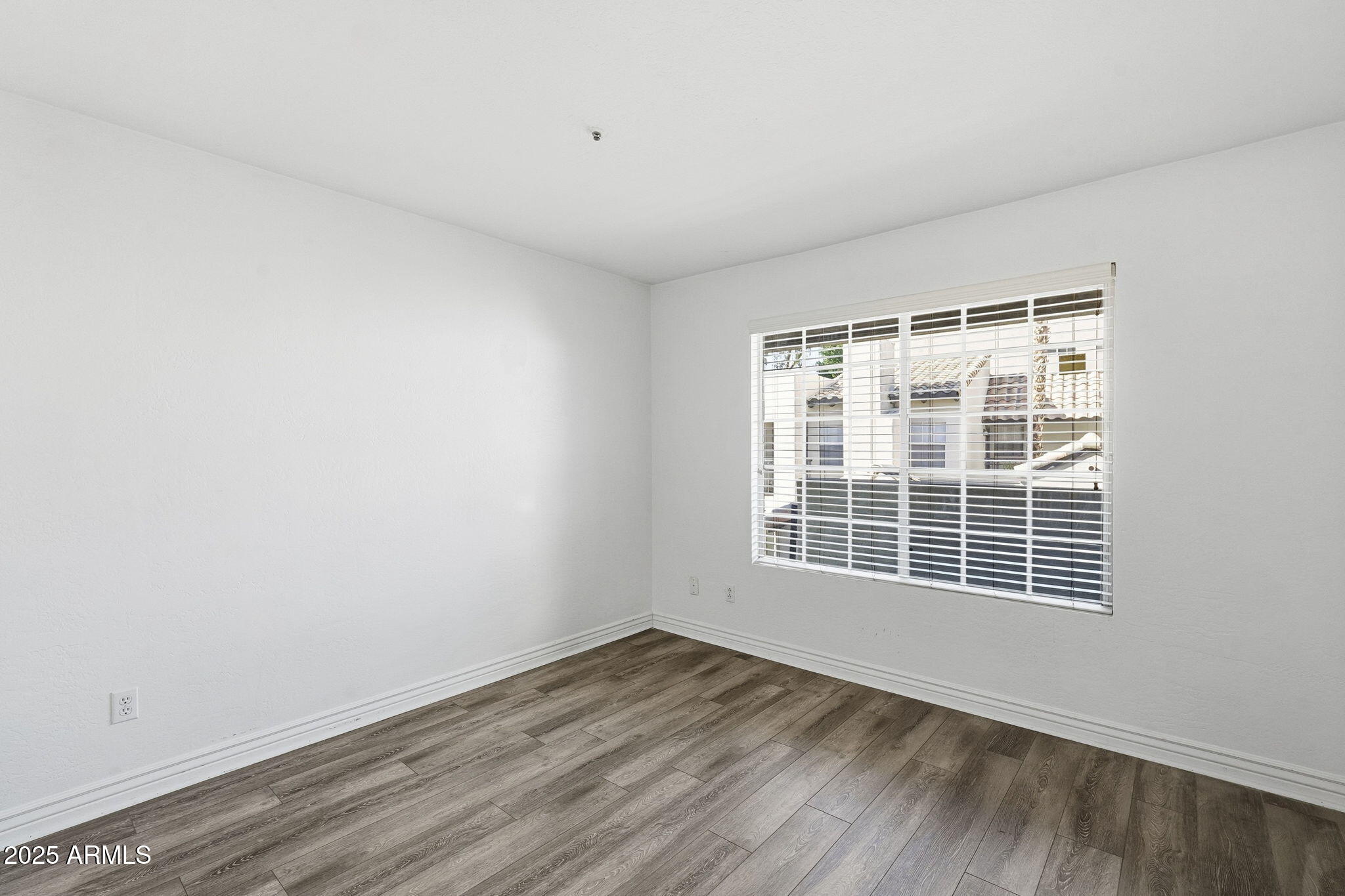 14145 North 92nd Street, Unit 2028 Scottsdale, AZ 85260 - Photo 16 of 24 a view of an empty room with wooden floor and a window