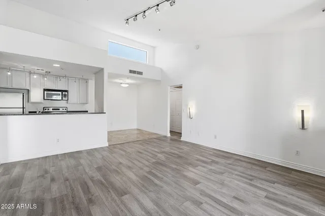 a view of empty room with kitchen and fireplace