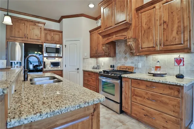 a kitchen with stainless steel appliances granite countertop a sink a stove and a wooden cabinets