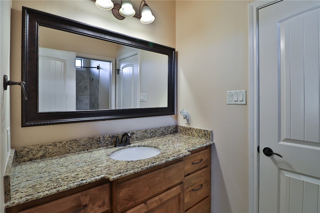 3900 Ambrose Court Bryan, TX 77808 - Photo 28 of 34 a bathroom with a granite countertop sink and a mirror