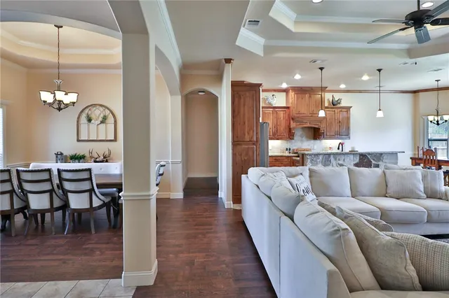 a living room with furniture kitchen view and a chandelier