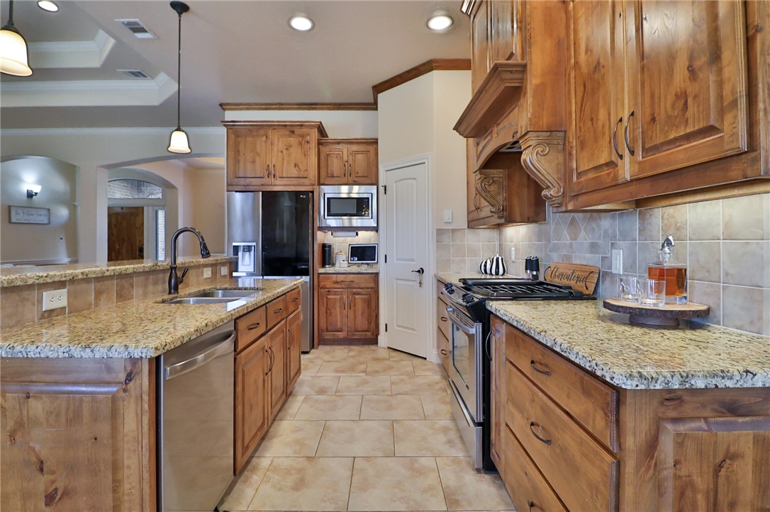 3900 Ambrose Court Bryan, TX 77808 - Photo 9 of 34 a kitchen with stainless steel appliances granite countertop a sink a stove and a wooden cabinets