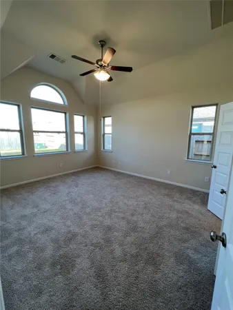 an empty room with windows and fan chandelier