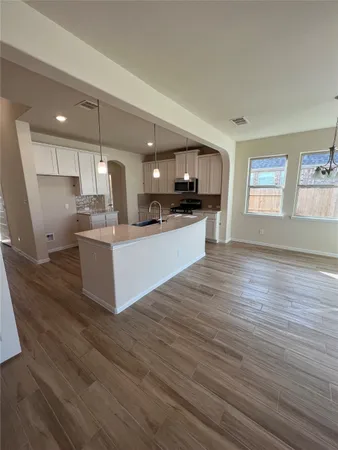 a large kitchen with cabinets wooden floor and stainless steel appliances