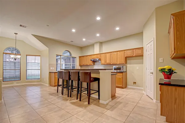 a open kitchen with stainless steel appliances granite countertop a refrigerator dining table and chairs