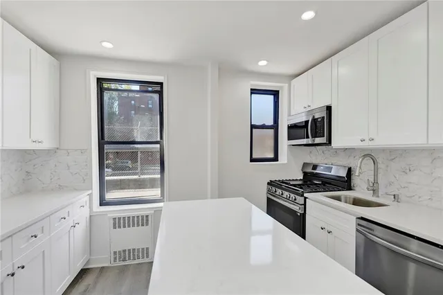 a kitchen with stainless steel appliances white cabinets and a stove top oven