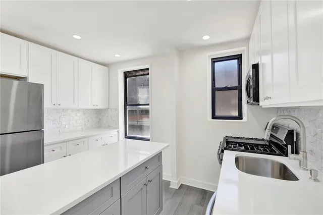 a kitchen with a refrigerator sink and white cabinets