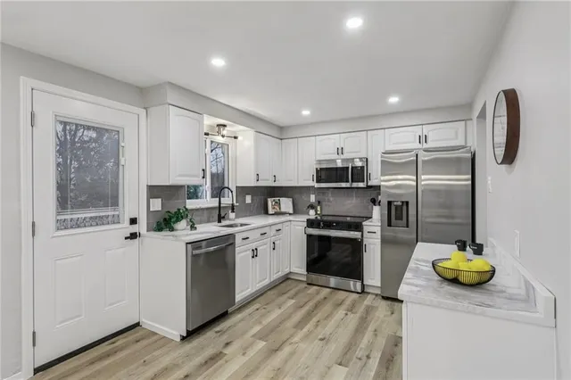 a kitchen with a refrigerator a stove a sink a counter space and cabinets