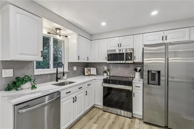 a kitchen with a sink stainless steel appliances and white cabinets