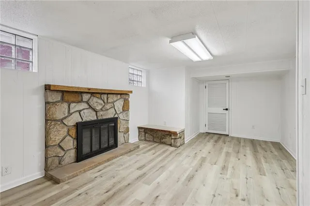 an empty room with wooden floor fireplace and windows