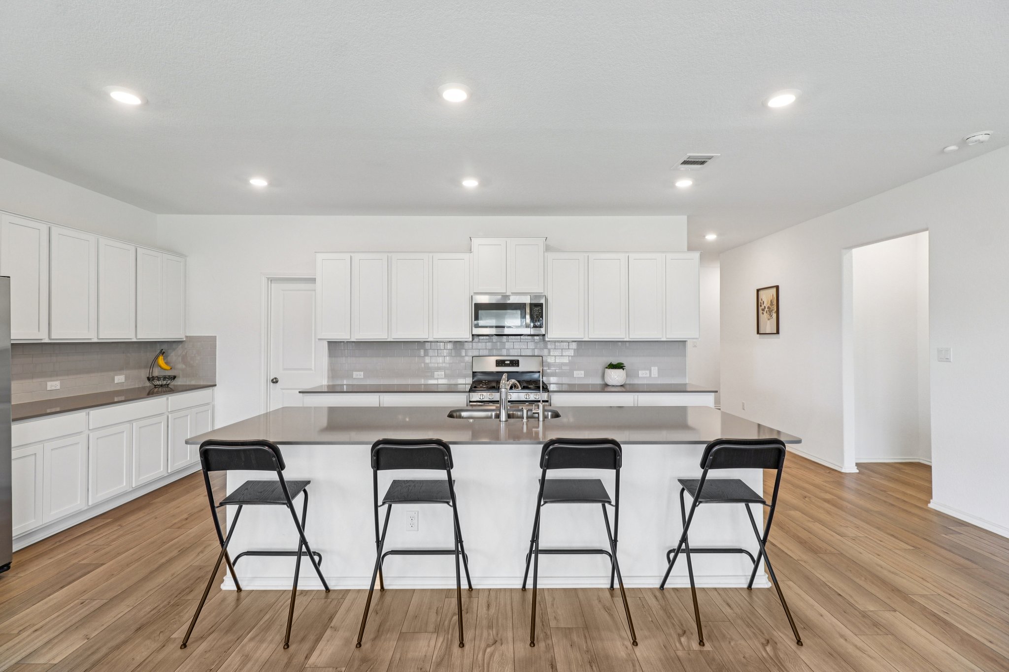 1201 Mallow Road Leander, TX 78641 - Photo 16 of 40 a kitchen with stainless steel appliances kitchen island granite countertop a dining table chairs and white cabinets