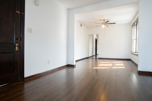 2519 North Pulaski Road Chicago, IL 60639 - Photo 6 of 36 an empty room with wooden floor chandelier fan and windows