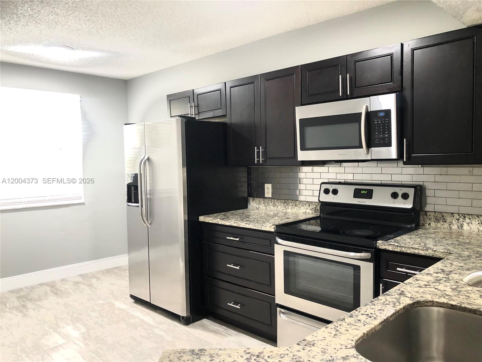 8761 Wiles Road, Unit 306 Coral Springs, FL 33067 - Photo 12 of 19 a kitchen with stainless steel appliances kitchen island granite countertop a stove a refrigerator and a microwave