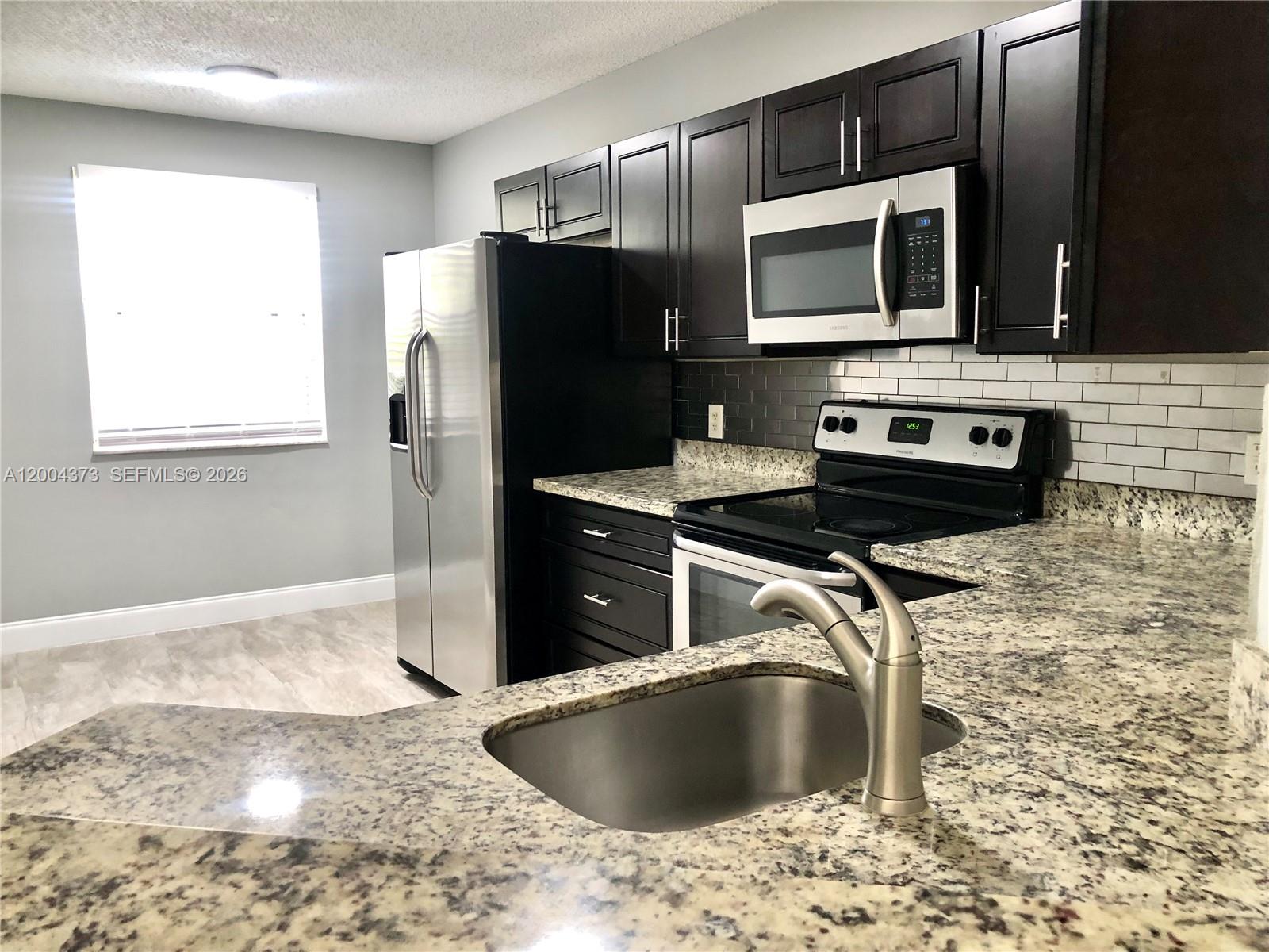 8761 Wiles Road, Unit 306 Coral Springs, FL 33067 - Photo 13 of 19 a kitchen with stainless steel appliances granite countertop a sink stove and microwave