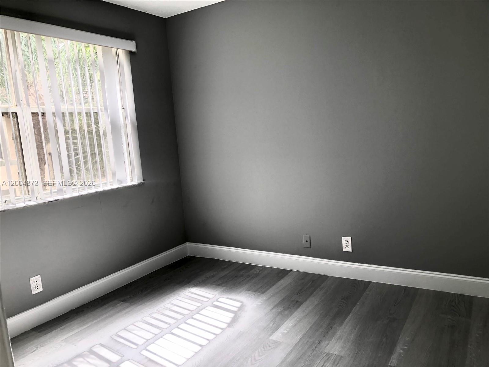 8761 Wiles Road, Unit 306 Coral Springs, FL 33067 - Photo 16 of 19 an empty room with wooden floor and windows