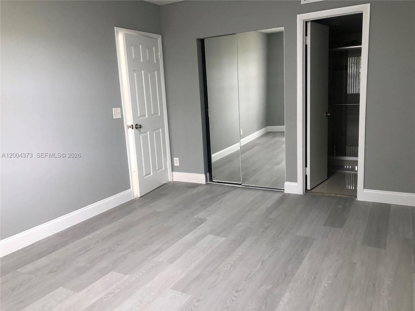 8761 Wiles Road, Unit 306 Coral Springs, FL 33067 - Photo 17 of 19 an empty room with wooden floor & windows