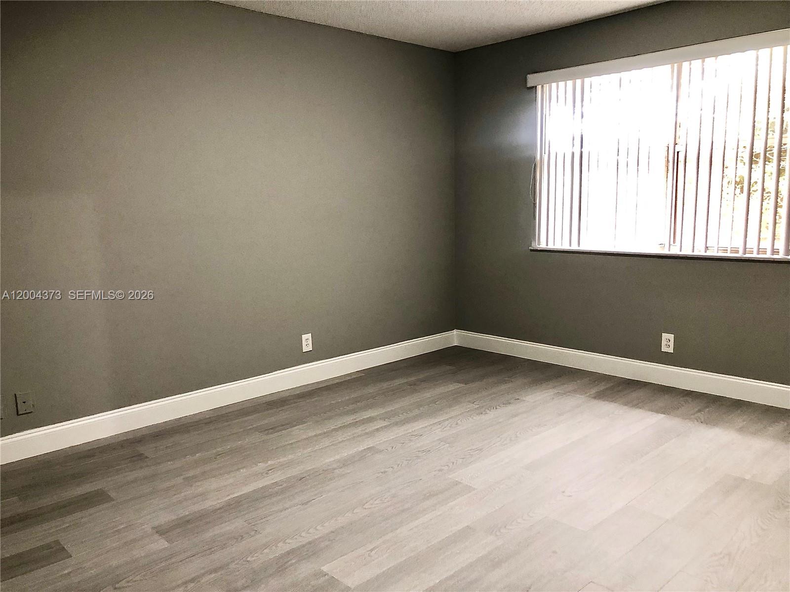 8761 Wiles Road, Unit 306 Coral Springs, FL 33067 - Photo 18 of 19 a view of an empty room with wooden floor and a window
