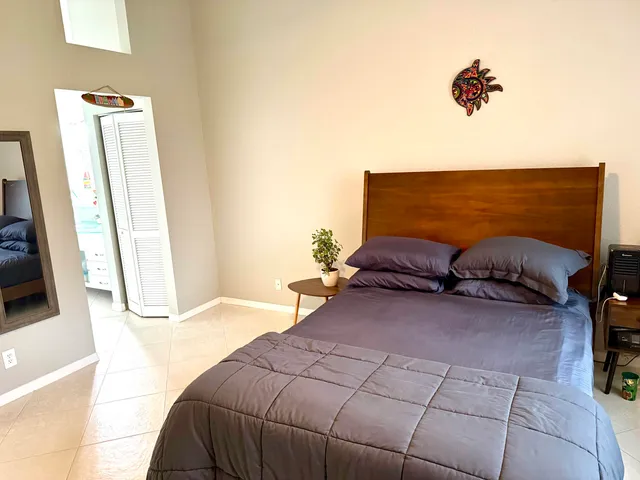 a bedroom with a large bed and a flat tv screen on dresser