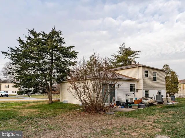a view of a white house with a big yard and large trees