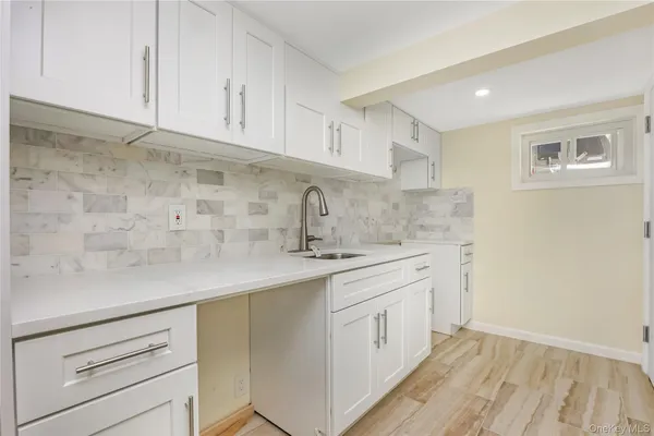 a kitchen with a sink dishwasher a stove and white cabinets with wooden floor