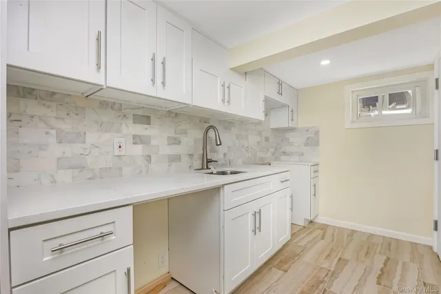 a kitchen with a sink dishwasher a stove and white cabinets with wooden floor