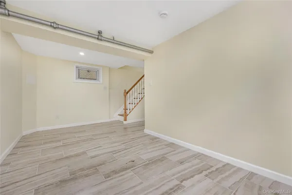 a view of an empty room with wooden floor and stairs