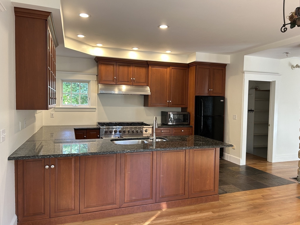 99 Tower Road Lincoln, MA 01773 - Photo 16 of 42 a kitchen with kitchen island granite countertop a sink cabinets and stainless steel appliances