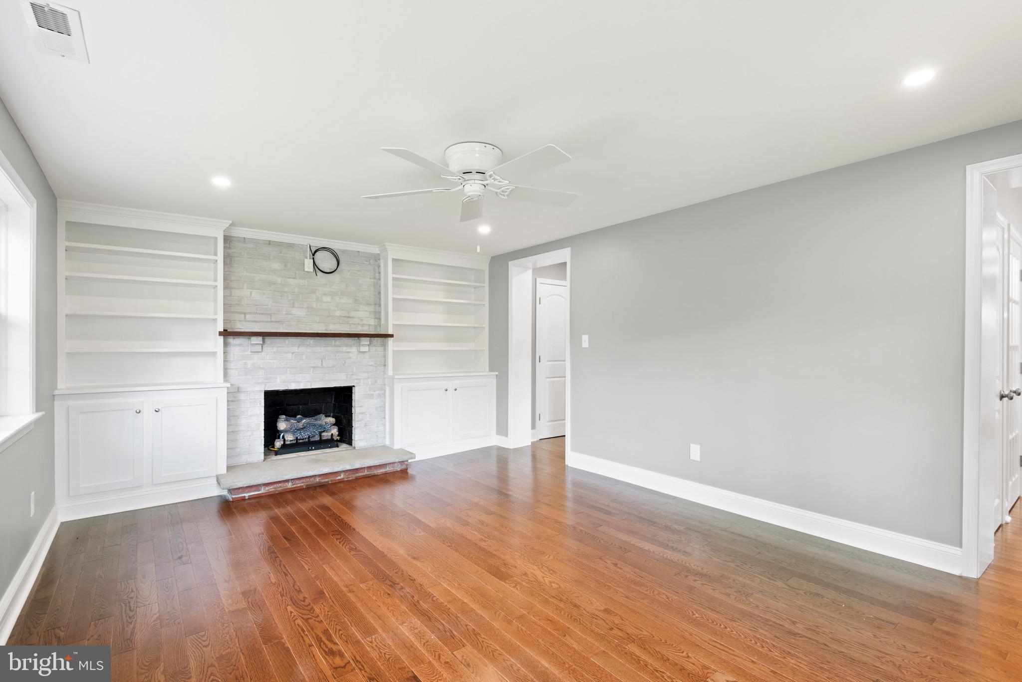 103 East Rose Valley Road Wallingford, PA 19086 - Photo 32 of 75 an empty room with wooden floor fireplace and windows