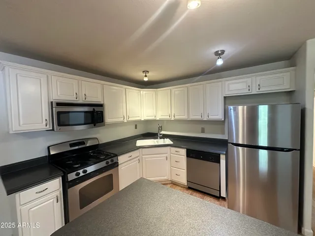 a kitchen with granite countertop a refrigerator stove and microwave