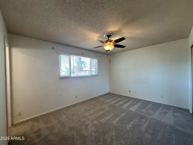 an empty room with a chandelier fan and a window