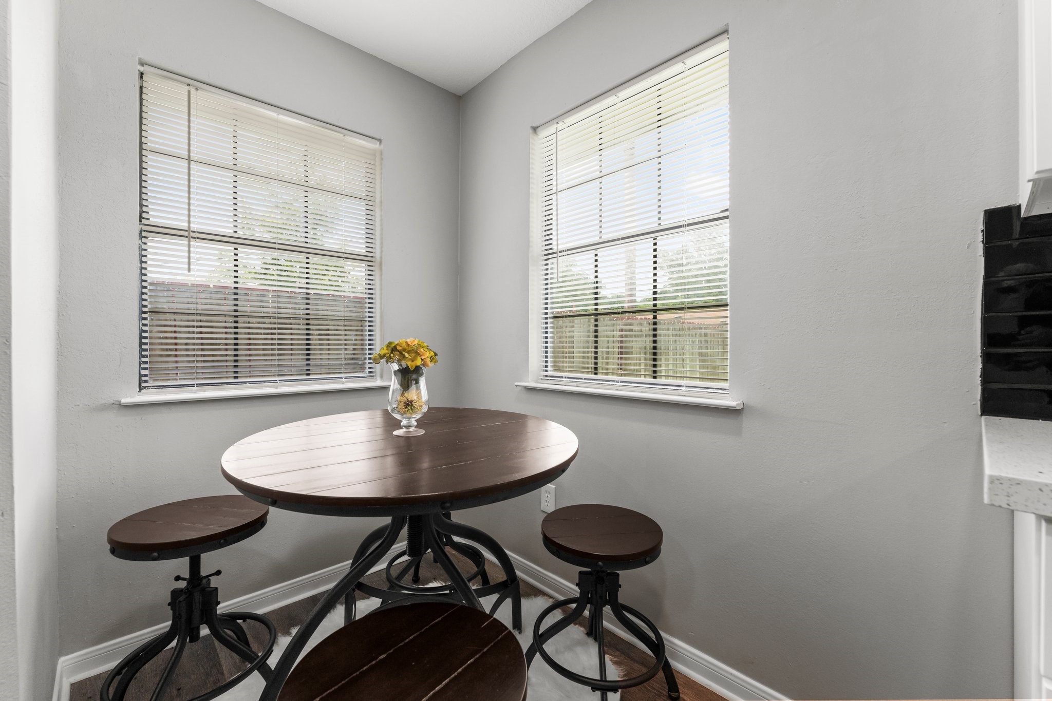 7280 Click Drive Beaumont, TX 77708 - Photo 12 of 39 Cozy breakfast nook with ample natural light from two large windows. Features a round wooden table with matching stools, perfect for casual dining. Neutral wall color complements the space.