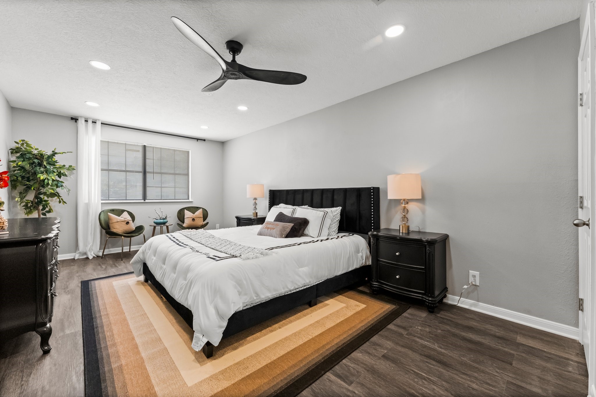 7280 Click Drive Beaumont, TX 77708 - Photo 15 of 39 This bedroom features a modern design with neutral tones, a cozy bed, and stylish furniture. It has ample natural light from a large window, complemented by elegant lighting fixtures and a ceiling fan. Ideal for comfort and relaxation.