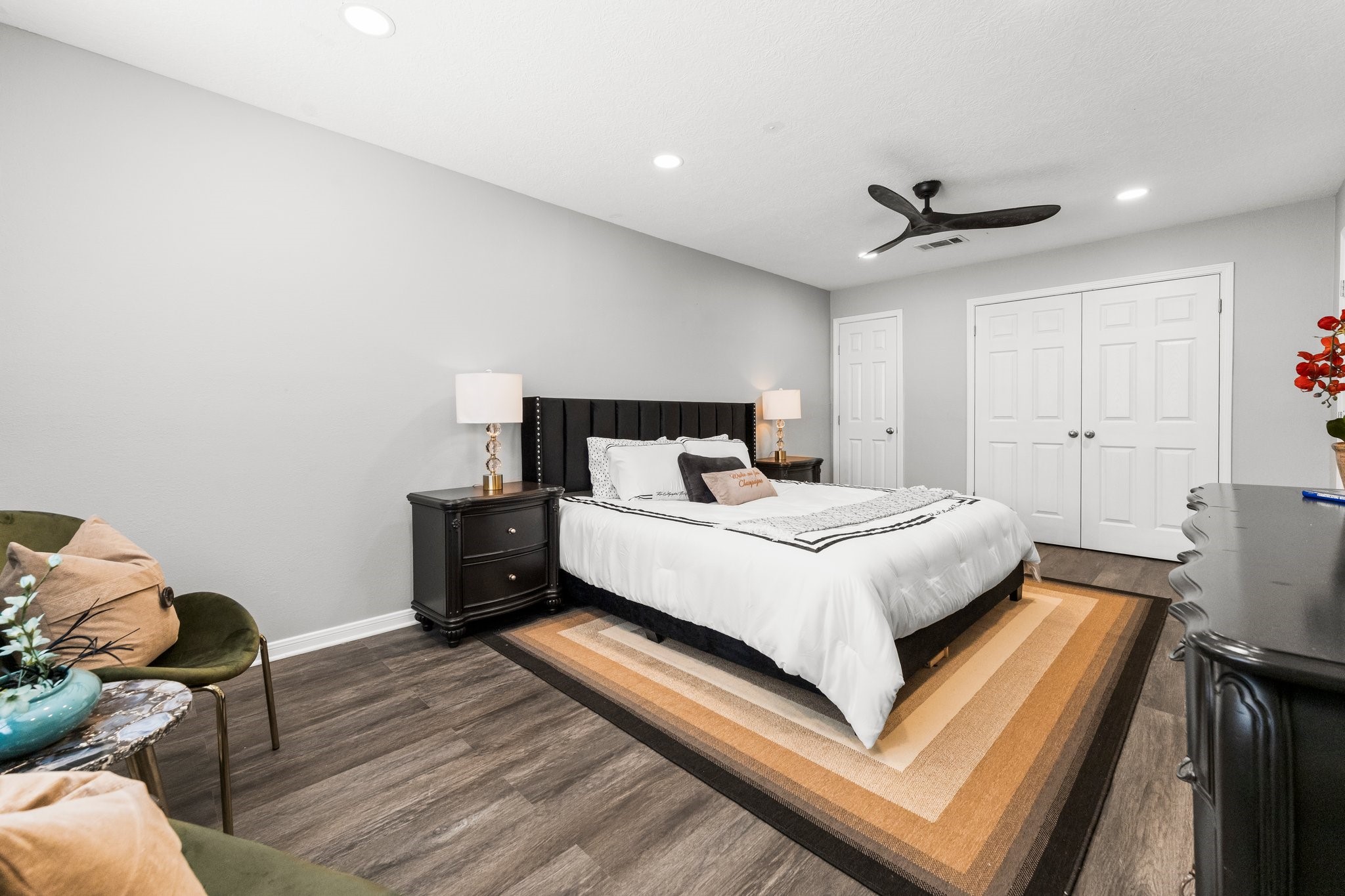 7280 Click Drive Beaumont, TX 77708 - Photo 16 of 39 This modern bedroom features a comfortable bed with a stylish headboard, flanked by matching nightstands and lamps. The room is accented by a neutral color palette, wood-look flooring, and a sleek ceiling fan. Ample closet space is available with double doors.