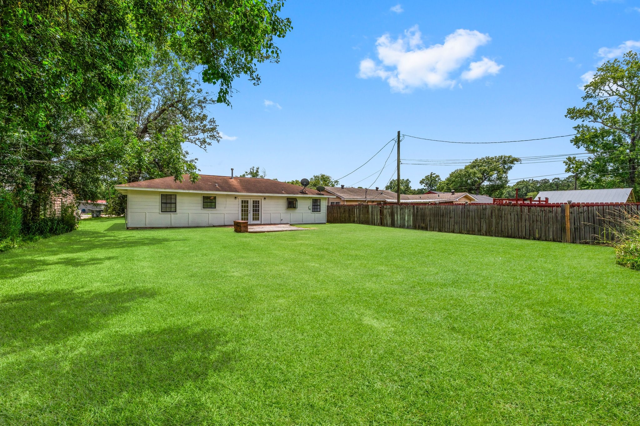 7280 Click Drive Beaumont, TX 77708 - Photo 25 of 39 Spacious backyard with lush green lawn, perfect for outdoor activities. The property is fenced for privacy and features a single-story home with a patio area, ideal for relaxing or entertaining.