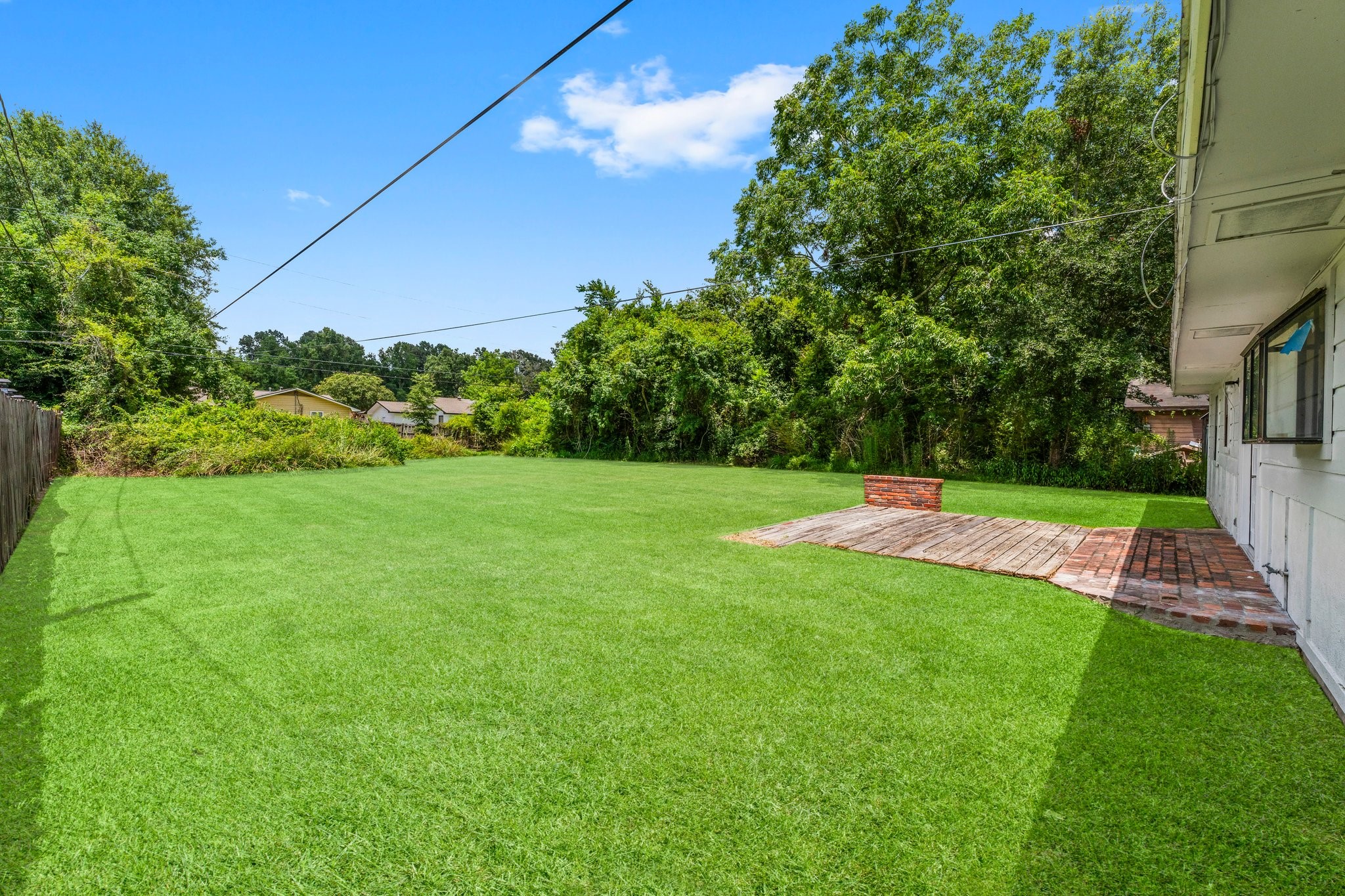 7280 Click Drive Beaumont, TX 77708 - Photo 26 of 39 Spacious backyard with a lush green lawn, bordered by trees for privacy. Features a small brick patio area, ideal for outdoor gatherings or relaxation.