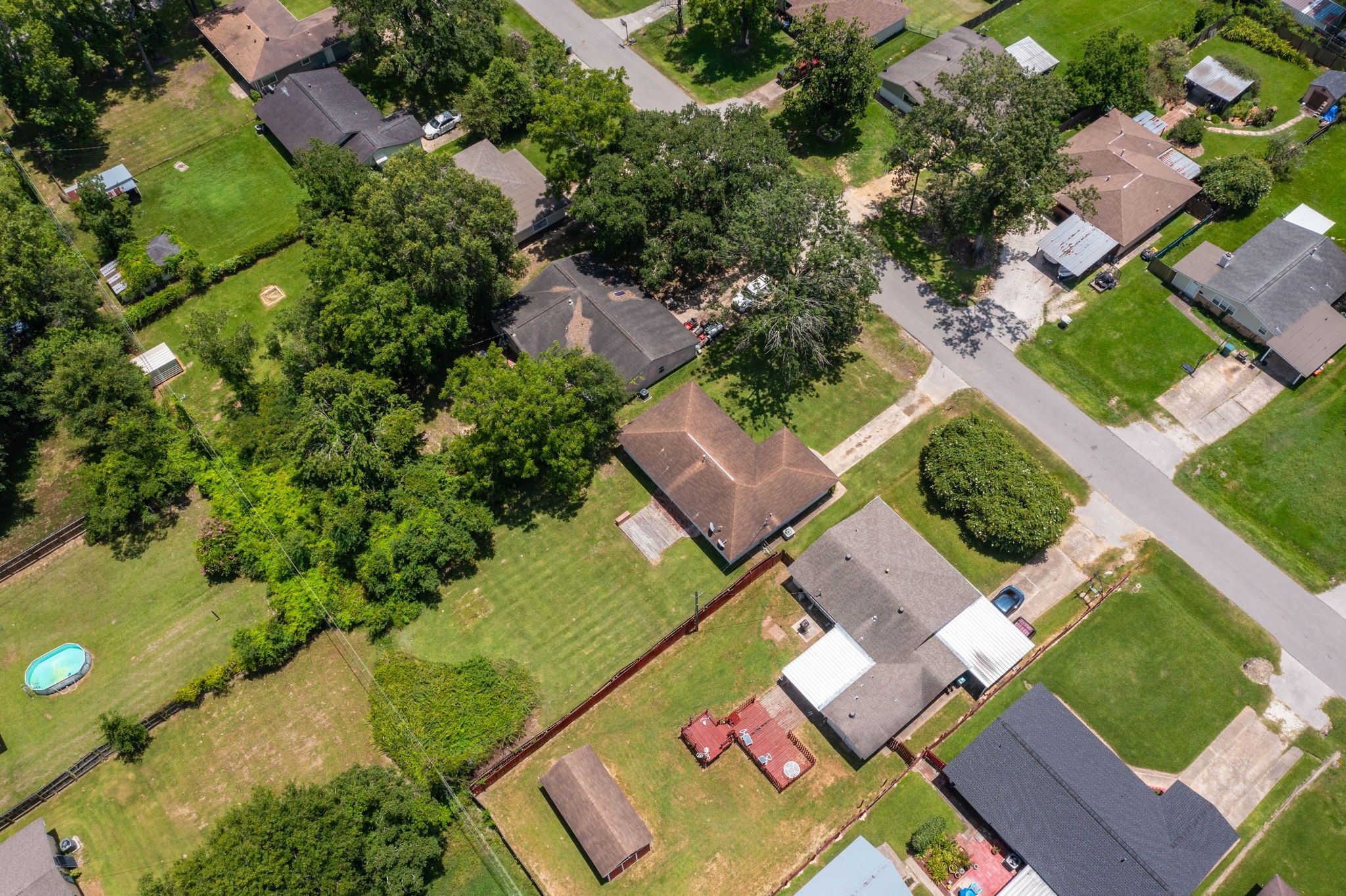7280 Click Drive Beaumont, TX 77708 - Photo 31 of 39 This aerial view showcases a residential neighborhood featuring single-family homes with spacious yards. The area is lush with greenery and mature trees, offering a serene suburban setting. The presence of well-maintained lawns and a few backyard amenities, like a pool, adds to the appeal for potential homeowners seeking a peaceful community.