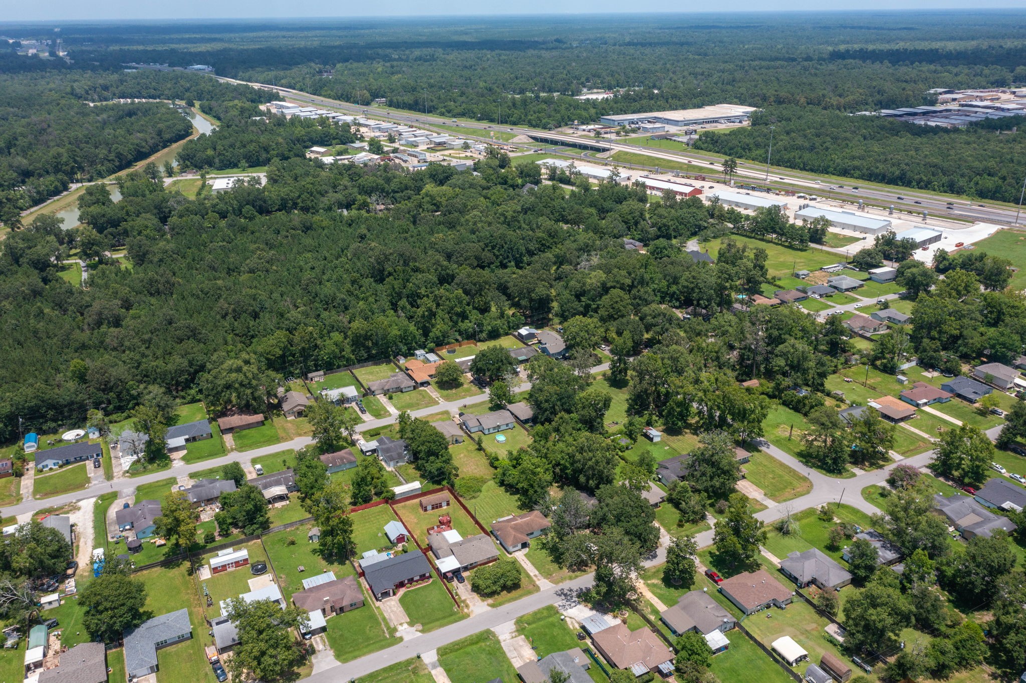 7280 Click Drive Beaumont, TX 77708 - Photo 33 of 39 This aerial view showcases a suburban neighborhood surrounded by lush greenery, with neatly arranged houses and spacious yards. Nearby, there's a major road providing easy access to amenities. Ideal for those seeking a blend of tranquility and convenience.