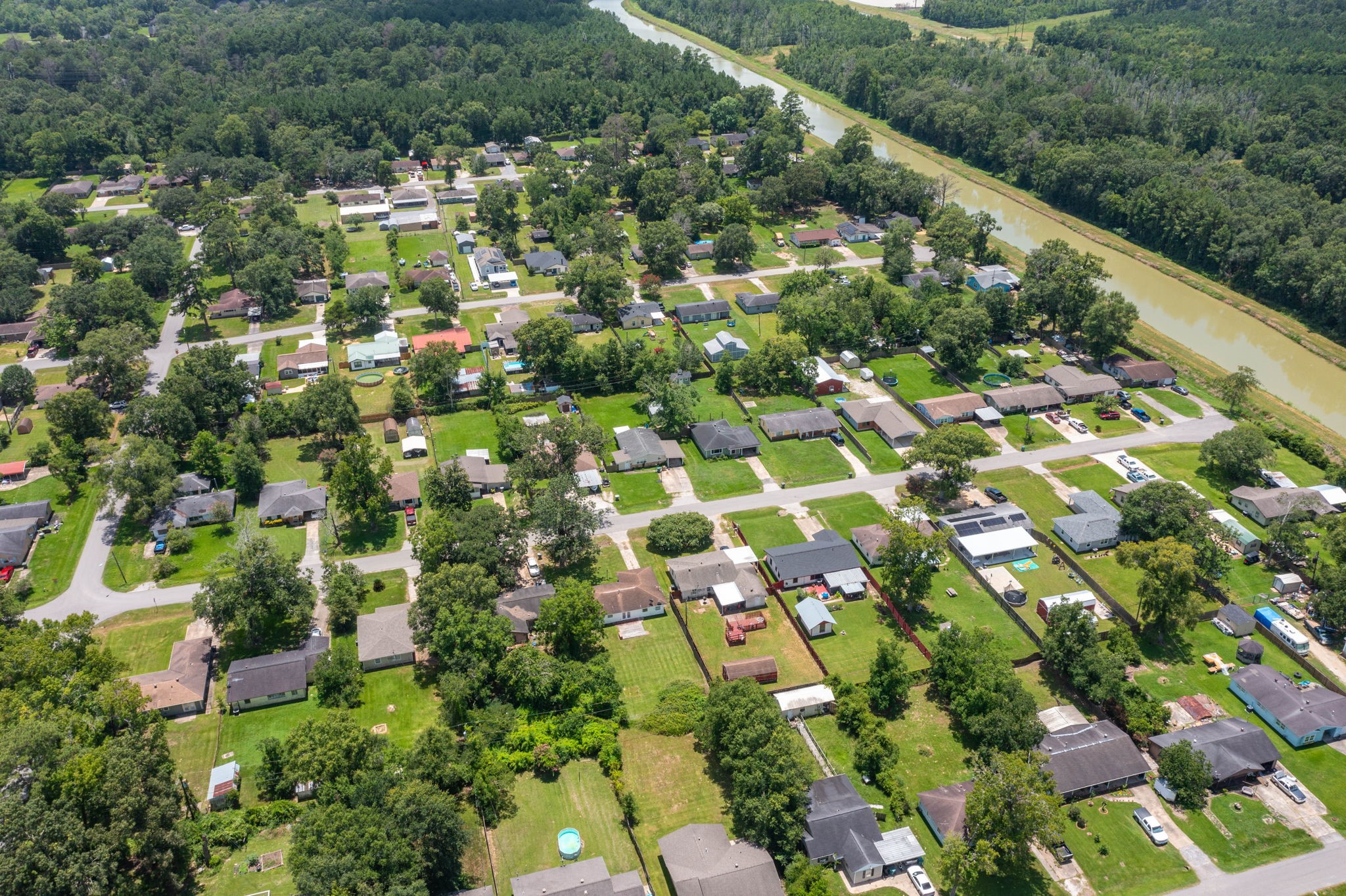 7280 Click Drive Beaumont, TX 77708 - Photo 36 of 39 This aerial photo showcases a quiet residential neighborhood with tree-lined streets and single-family homes. The area is lush with greenery and bordered by a winding river, offering a serene and picturesque setting.