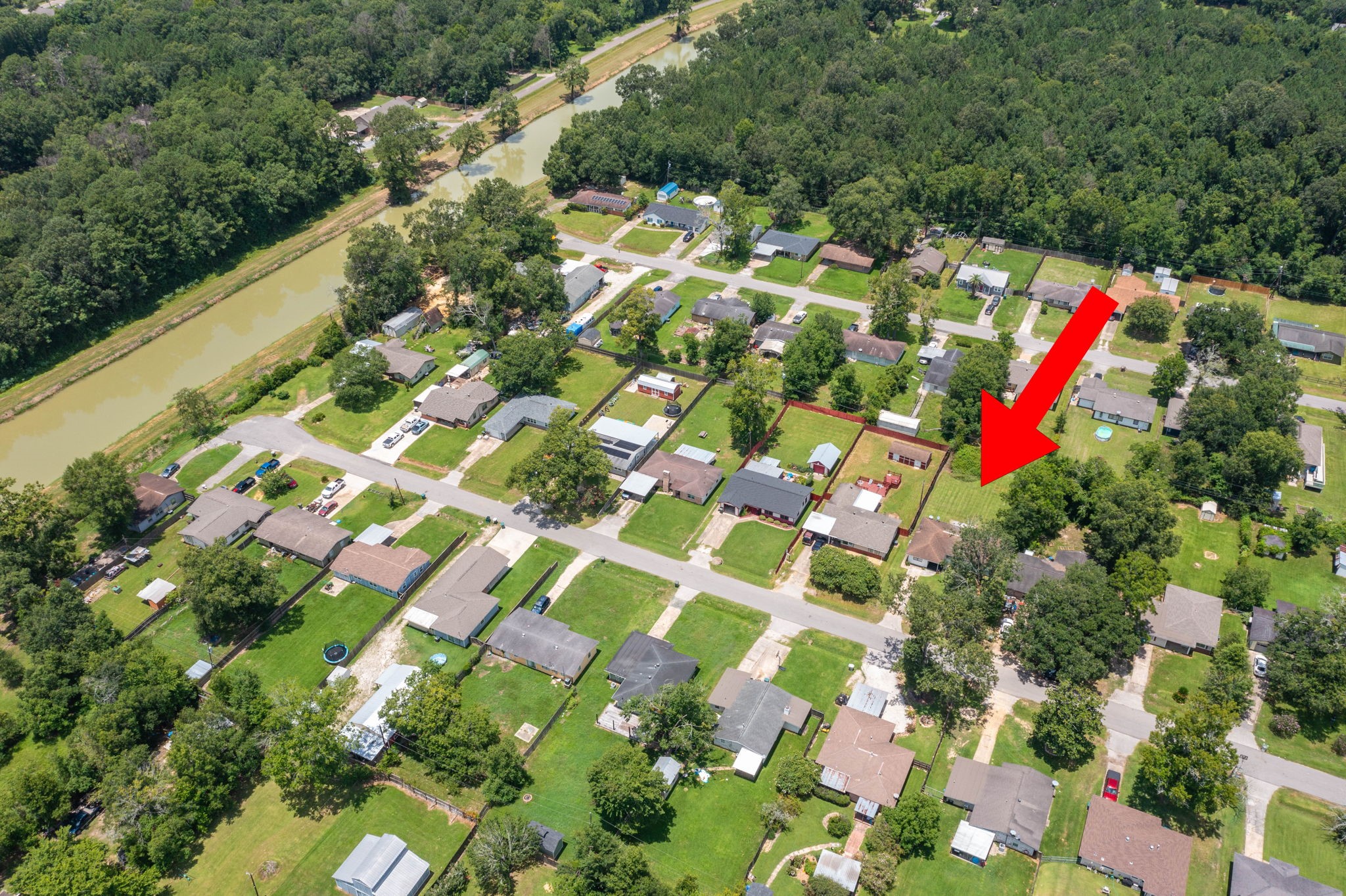7280 Click Drive Beaumont, TX 77708 - Photo 38 of 39 This aerial photo showcases a suburban neighborhood with tree-lined streets and single-family homes. The highlighted property is centrally located, featuring a spacious yard and proximity to a scenic waterway and wooded area, offering a peaceful, green setting.