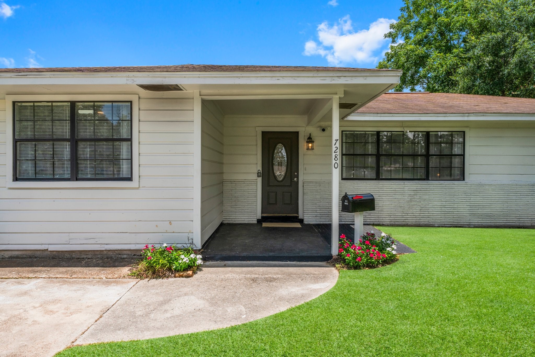 7280 Click Drive Beaumont, TX 77708 - Photo 4 of 39 Charming single-story home with a welcoming front porch and well-maintained exterior. Features include a black front door with a decorative oval window, white siding, and large windows for natural light. A neat lawn with colorful flower beds enhances curb appeal.
