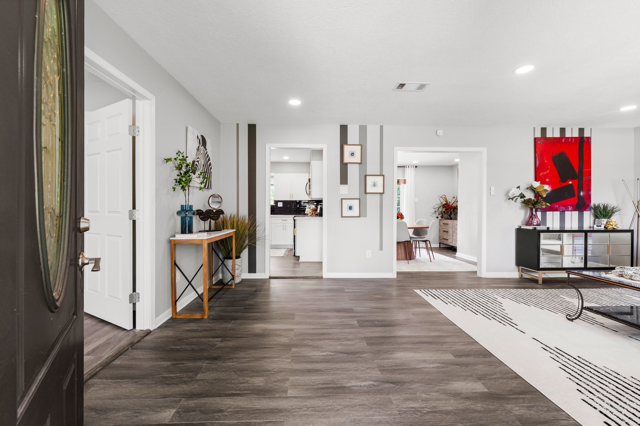 7280 Click Drive Beaumont, TX 77708 - Photo 5 of 39 This modern entryway features stylish wood flooring, contemporary art, and ample natural light. It leads to a bright kitchen and dining area, offering an inviting and open layout for comfortable living.