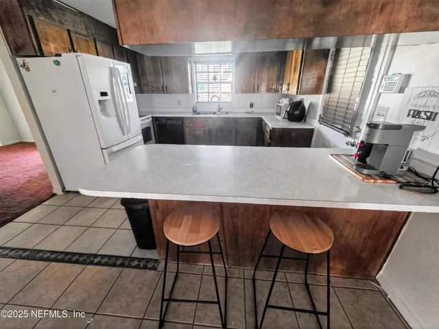 a living room with stainless steel appliances furniture a rug a fireplace and a counter top space