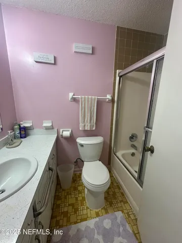 a bathroom with a granite countertop toilet sink and mirror