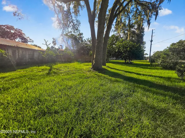 a view of a house with a big yard and large trees