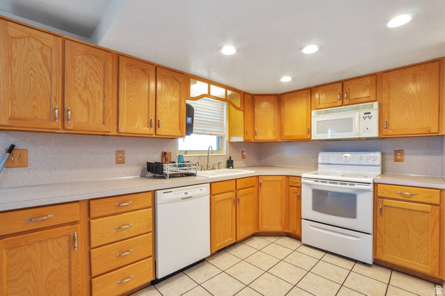 1057 North 700 West Clinton, UT 84015 - Photo 4 of 15 Kitchen featuring white appliances, light countertops, light tile patterned flooring, wood finish cabinets, and recessed lighting