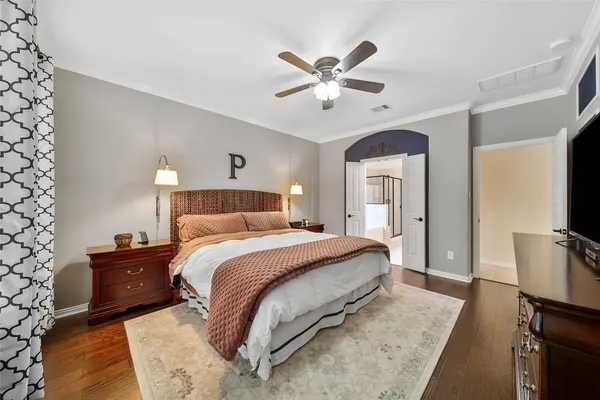 a spacious bedroom with a large bed and a flat tv screen on dresser