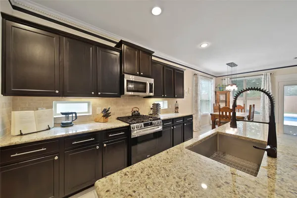 a kitchen with granite countertop a sink stainless steel appliances and cabinets